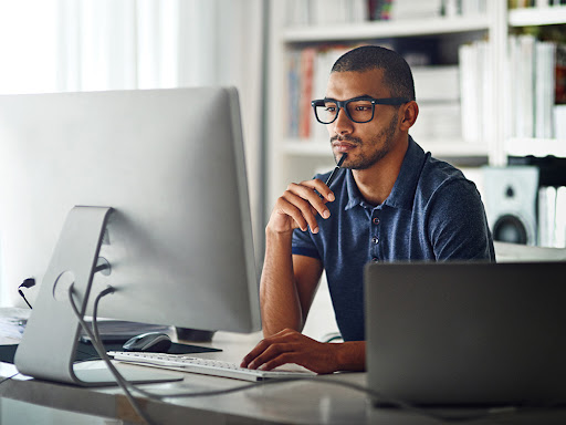 man sitting at his desk deep in thought staring at his computer