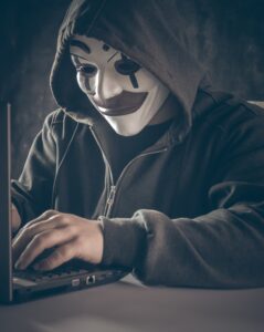 Phisher at computer wearing mask