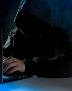 Hooded hacker on computer
