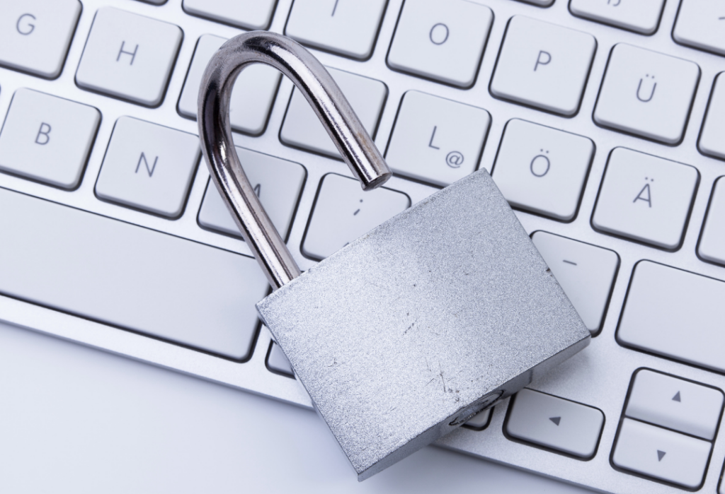 White unlocked padlock resting on top of a white keyboard.