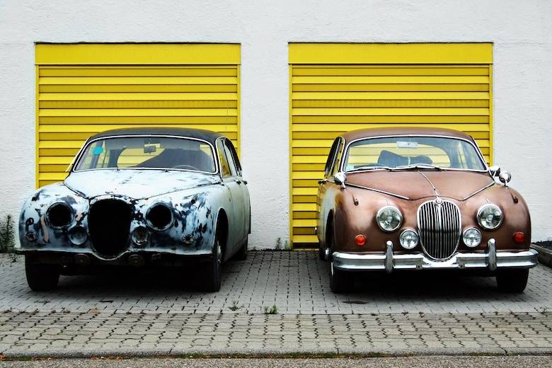 Vintage blue and orange cars in front of a yellow garage
