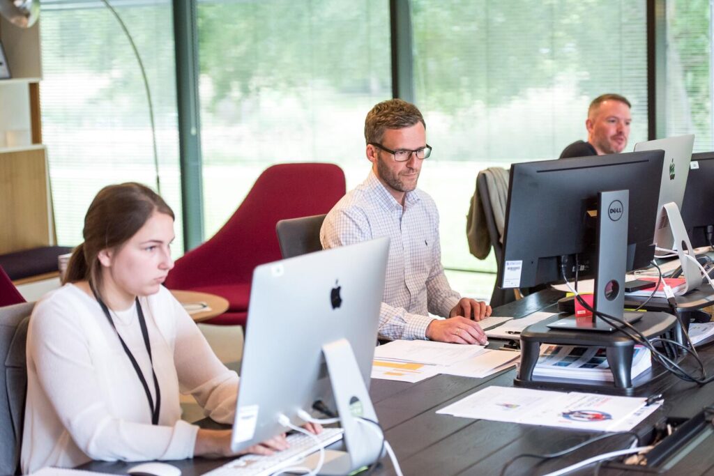 Group of people working in a mixed-OS, open-concept office.