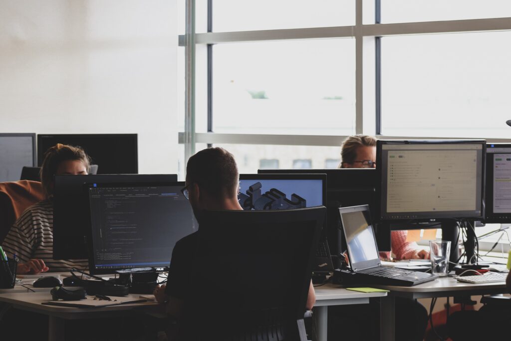 A group of workers using dual-screen computers in an open-concept office.