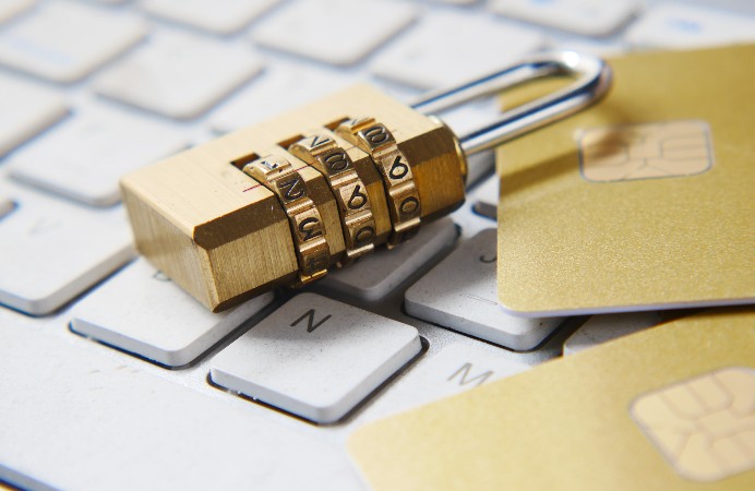 Golden lock and golden credit cards sitting on top of a keyboard.