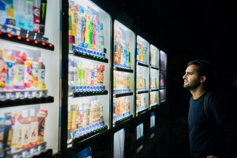 person looking at a wall of sodas, overwhelmed by the choice, questioning everything he's ever done in life