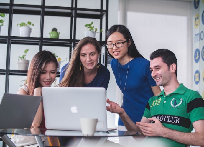 Coworkers using a Mac laptop to collaborate on a project