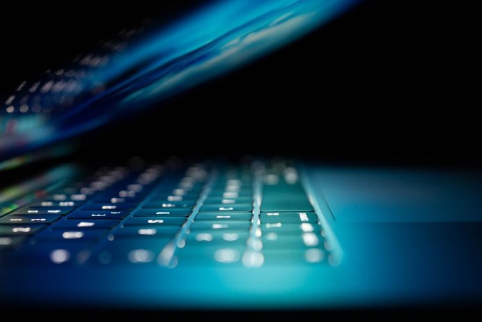 Laptop keyboard illuminated by the screen as it's closed.