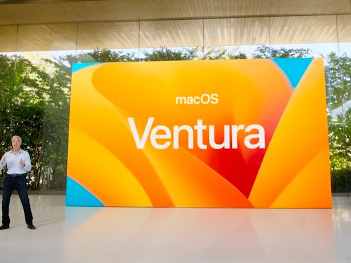 Man standing next to a large macOS Ventura billboard