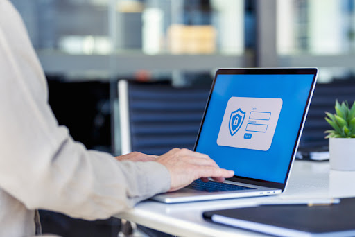 Businessman logging on to a password protected website. There are login and password fields and a sign in button. There is also a shield and lock graphic