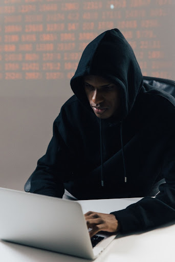 man working at a computer wearing hood