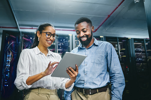 a man and woman looking at a tablet in a server room