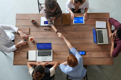 group sitting around a table with laptops in a business meeting