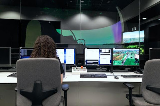 back of a persons head sitting at a desk looking at computer screens