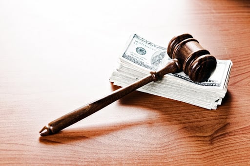 A judge's or auctioneer's gavel acts as a paperweight on a thick stack of banknotes. Payment, a fine, or bribery?