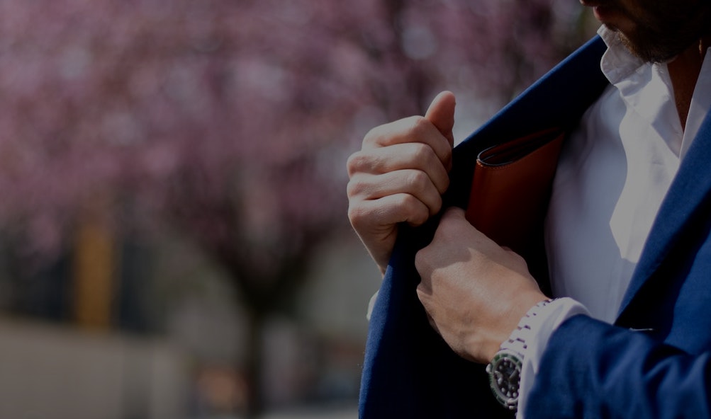 un homme fouillant dans la poche intérieure de son blazer