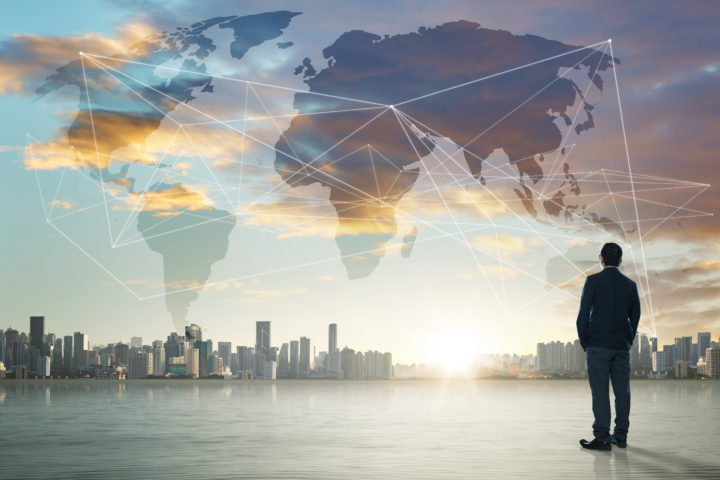 International business concept with businessman on city skyline background with network on map and sunlight