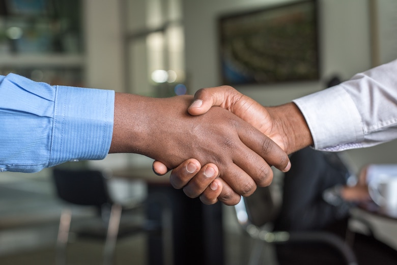 Two men shake hands in an office-type space.